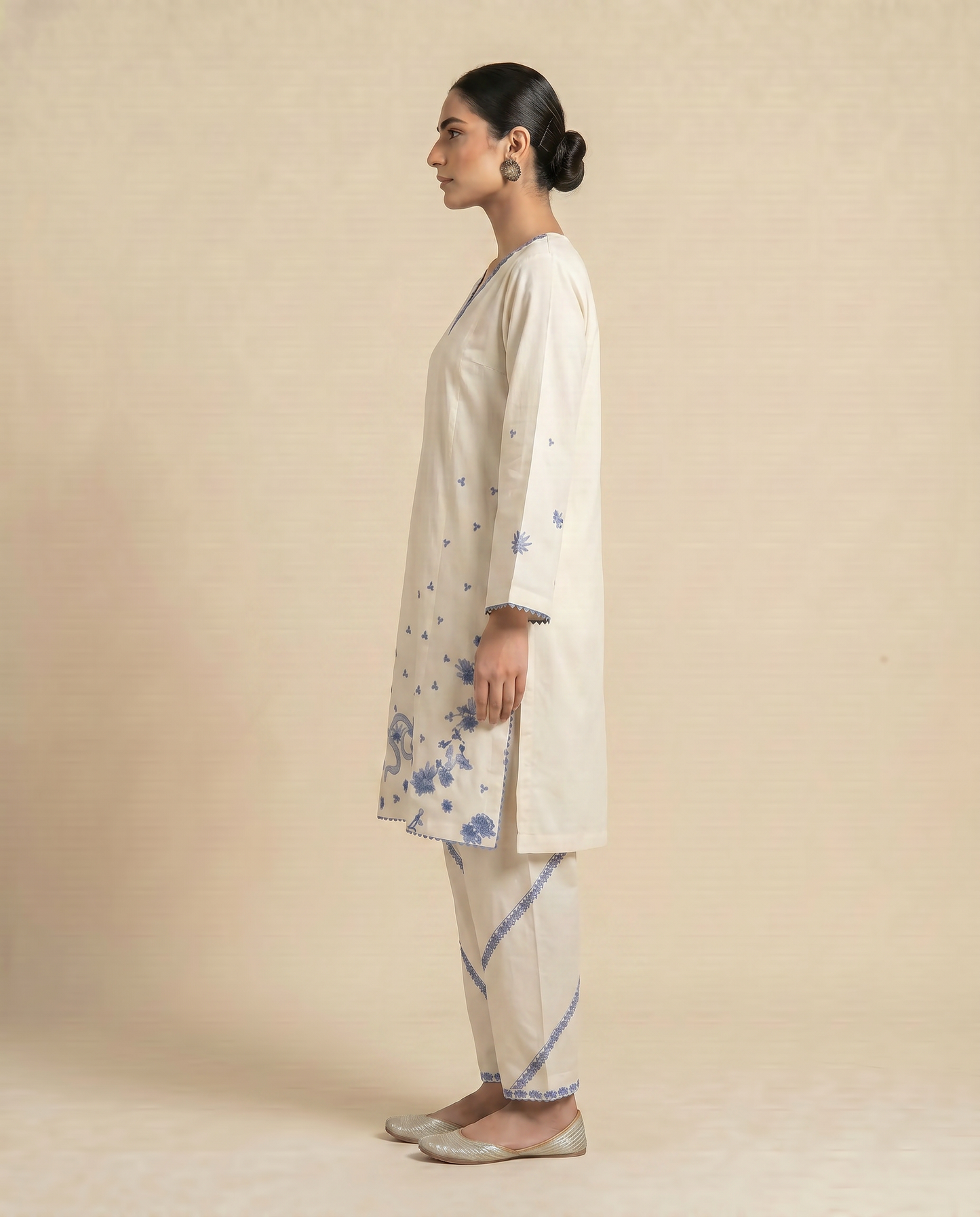 Woman wearing a beige kurta with floral patterns on a beige background