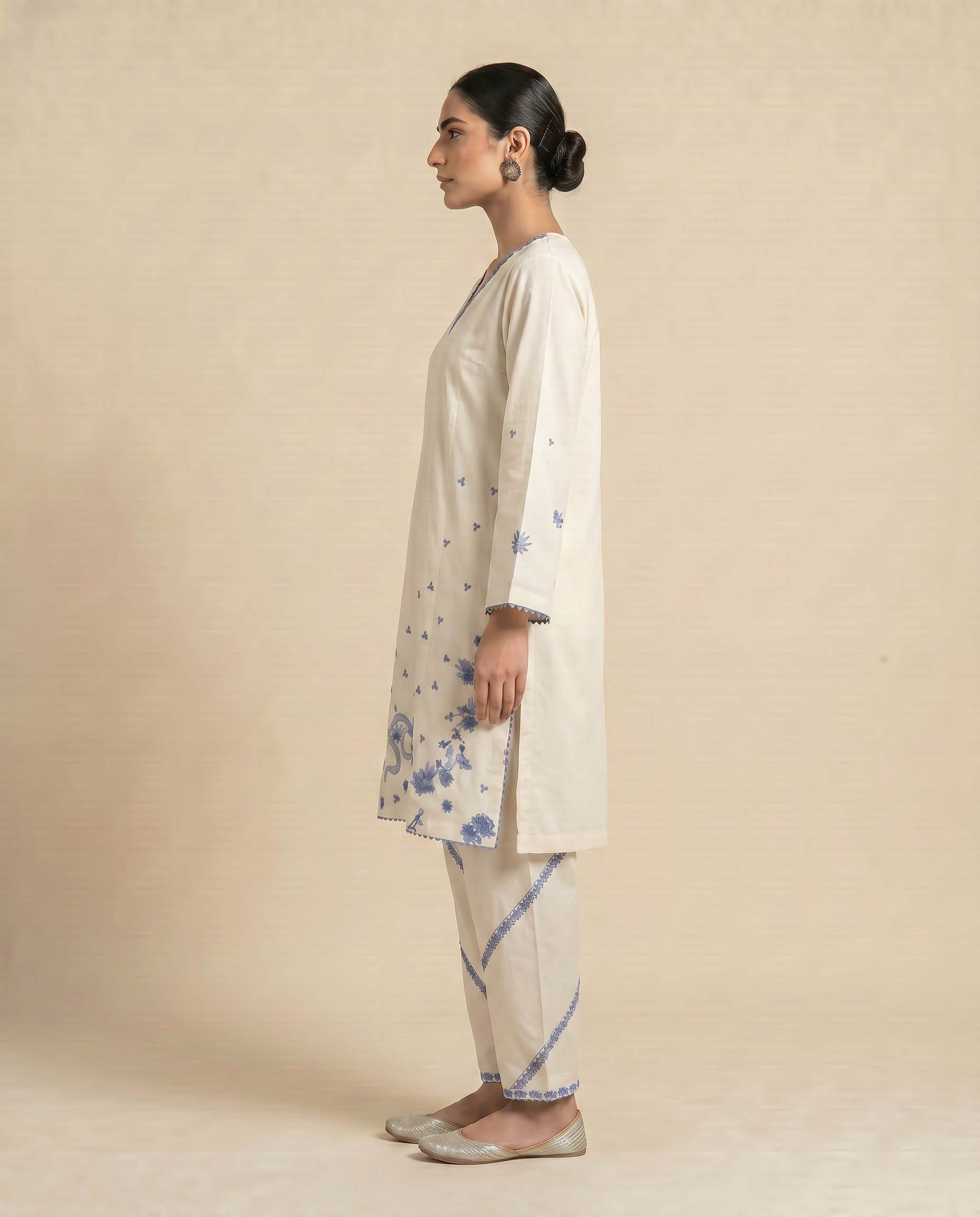 Woman wearing a beige kurta with floral patterns on a beige background